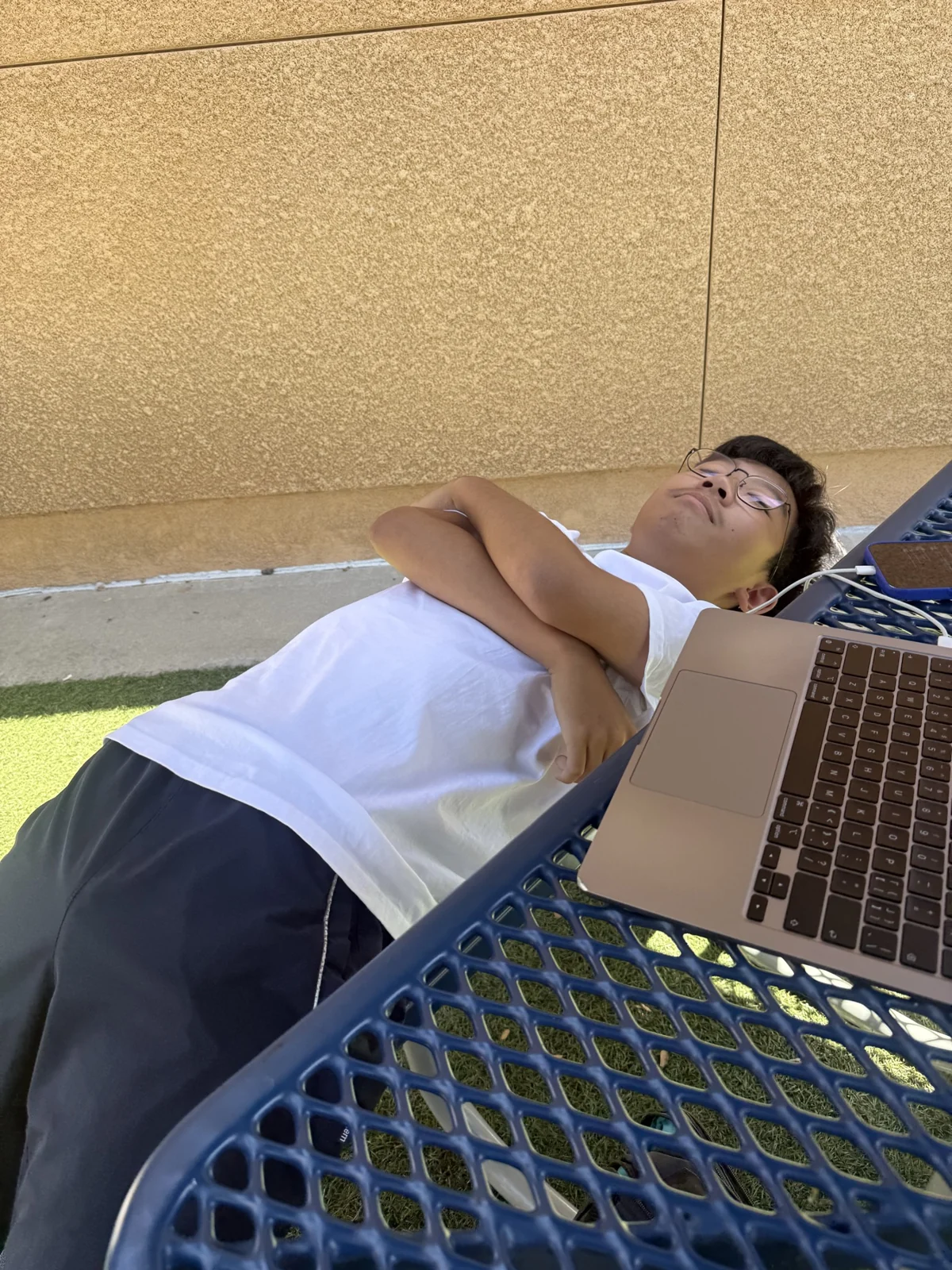 Leaning back on a bench beside a laptop